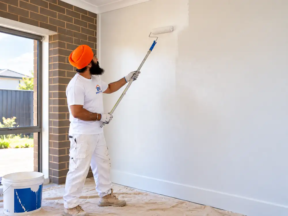 Interior painter applying a smooth coat of wall paint with a roller