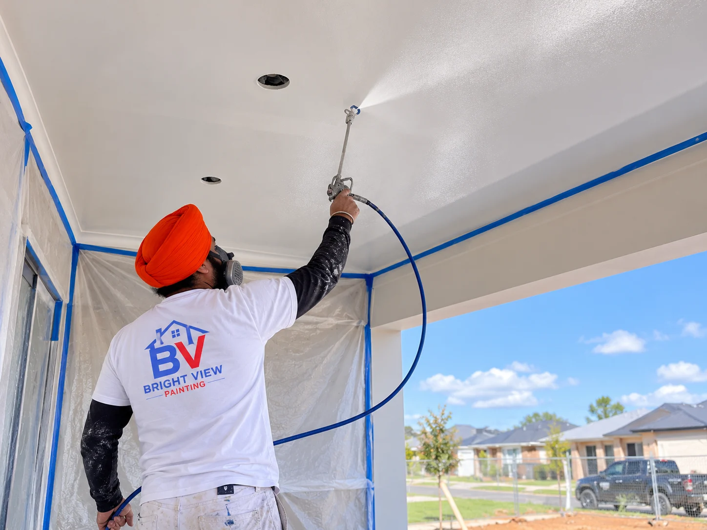 Painter spray applying an even coating to a ceiling